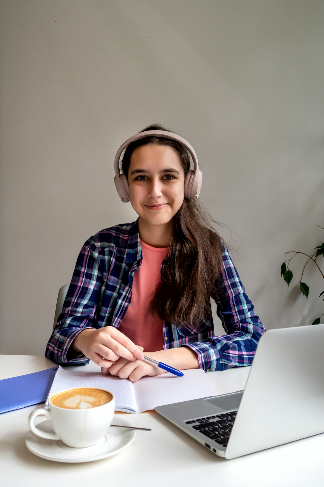 Distance learning. Teenager girl in pink headphones is engaged online by video conference on laptop