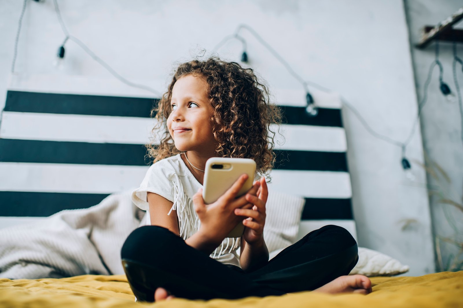 Smiling child using smartphone in bedroom